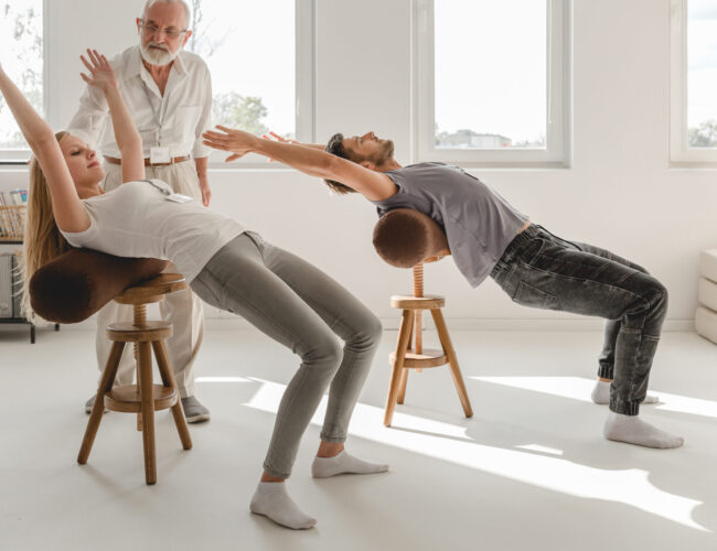 Two young people working on spine mobility stretching on a roller